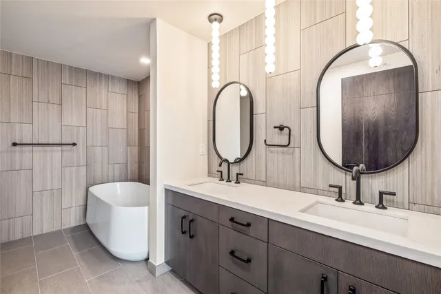 a bathroom with a double vanity sink mirror and bathtub