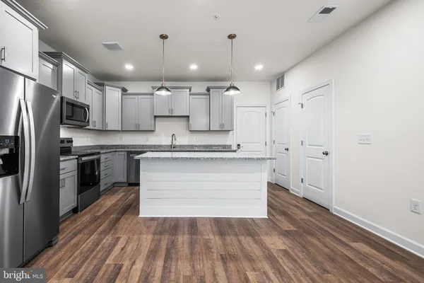 a kitchen with kitchen island a counter top space stainless steel appliances and cabinets