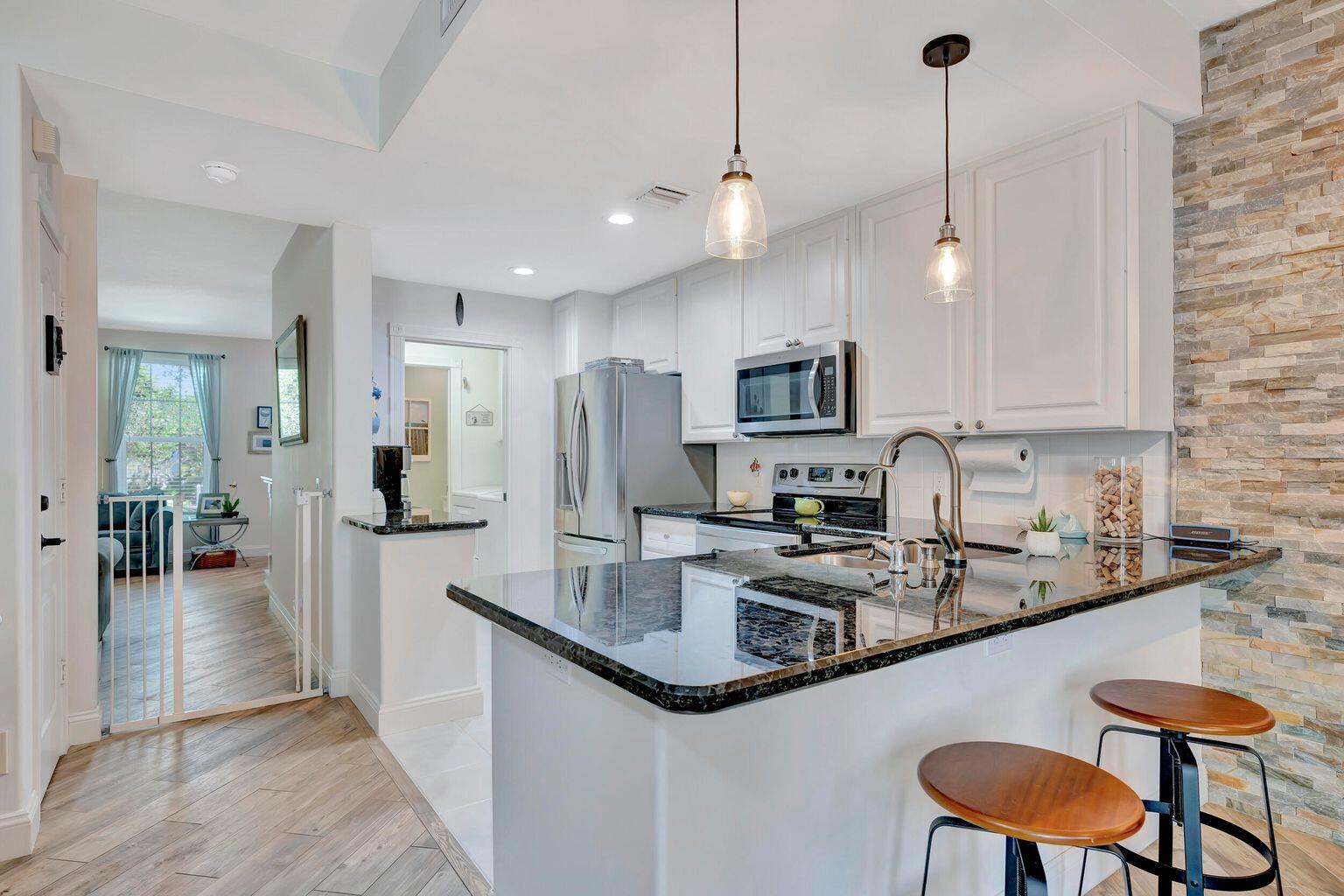 180 Freeport Drive Jupiter, FL 33458 - Photo 14 of 34 a kitchen with stainless steel appliances granite countertop a sink a stove a refrigerator and island with wooden floor