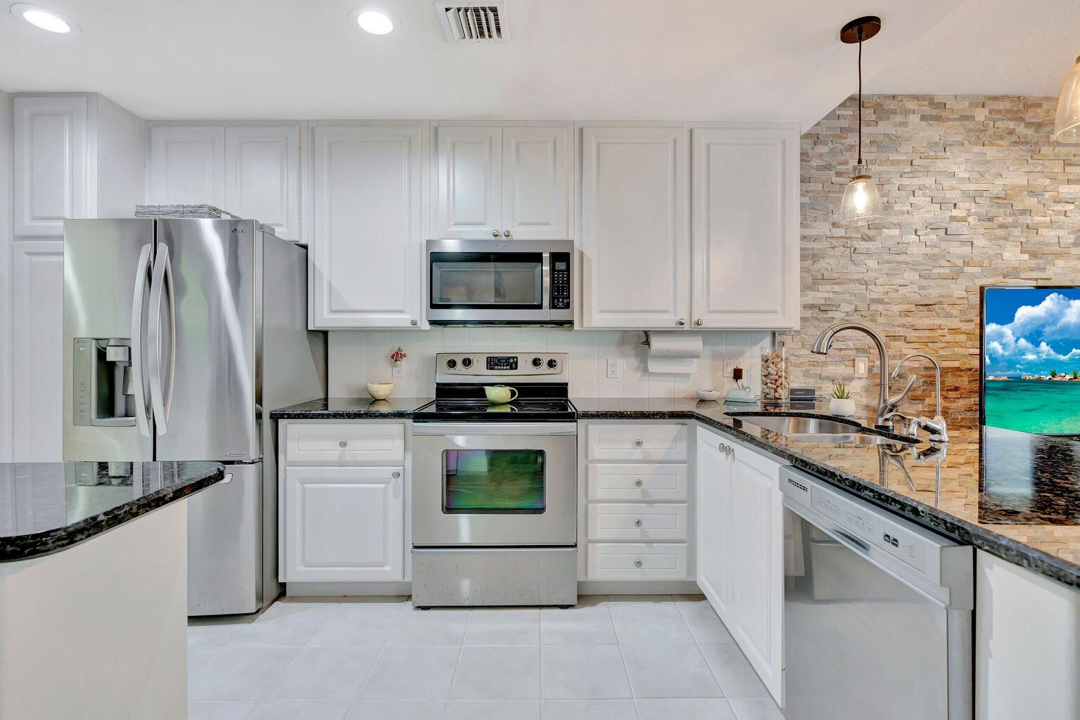 180 Freeport Drive Jupiter, FL 33458 - Photo 15 of 34 a kitchen with granite countertop a refrigerator sink and stainless steel appliances