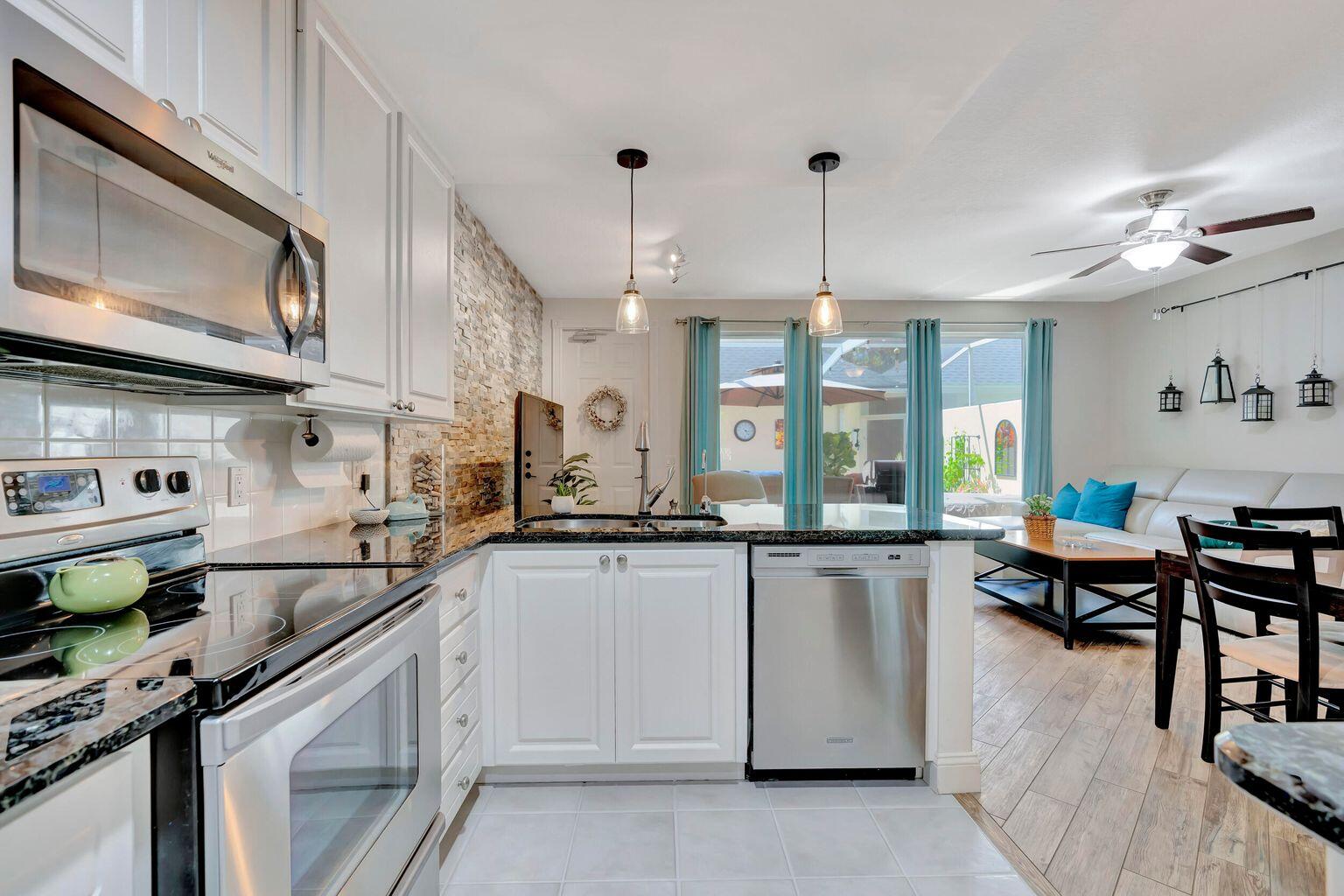 180 Freeport Drive Jupiter, FL 33458 - Photo 17 of 34 a kitchen with stainless steel appliances granite countertop a sink a stove and a wooden cabinets