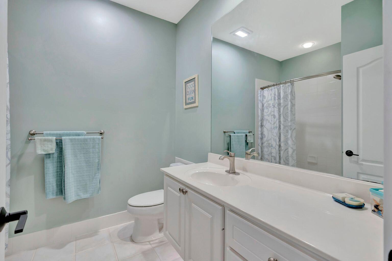 180 Freeport Drive Jupiter, FL 33458 - Photo 30 of 34 a bathroom with a granite countertop sink a toilet and a mirror