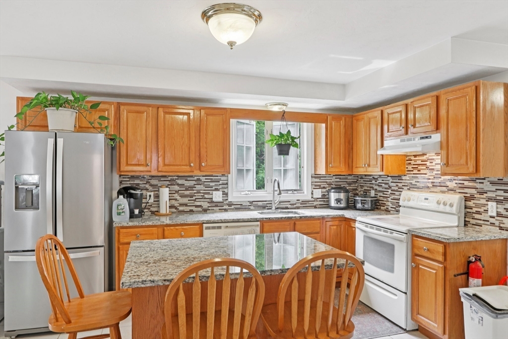 469 North Street Randolph, MA 02368 - Photo 18 of 42 a kitchen with stainless steel appliances granite countertop a refrigerator a sink a stove and island
