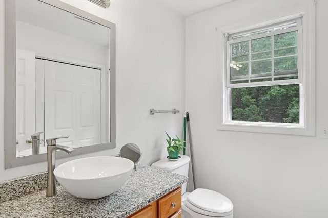 a bathroom with a granite countertop toilet a sink and a mirror