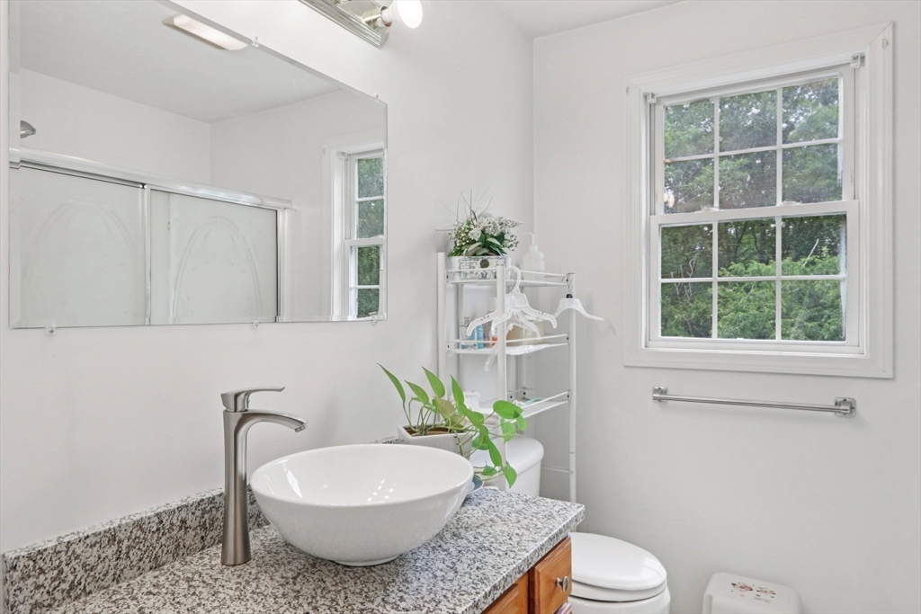 469 North Street Randolph, MA 02368 - Photo 24 of 42 a bathroom with a granite countertop toilet a sink a mirror and a shower
