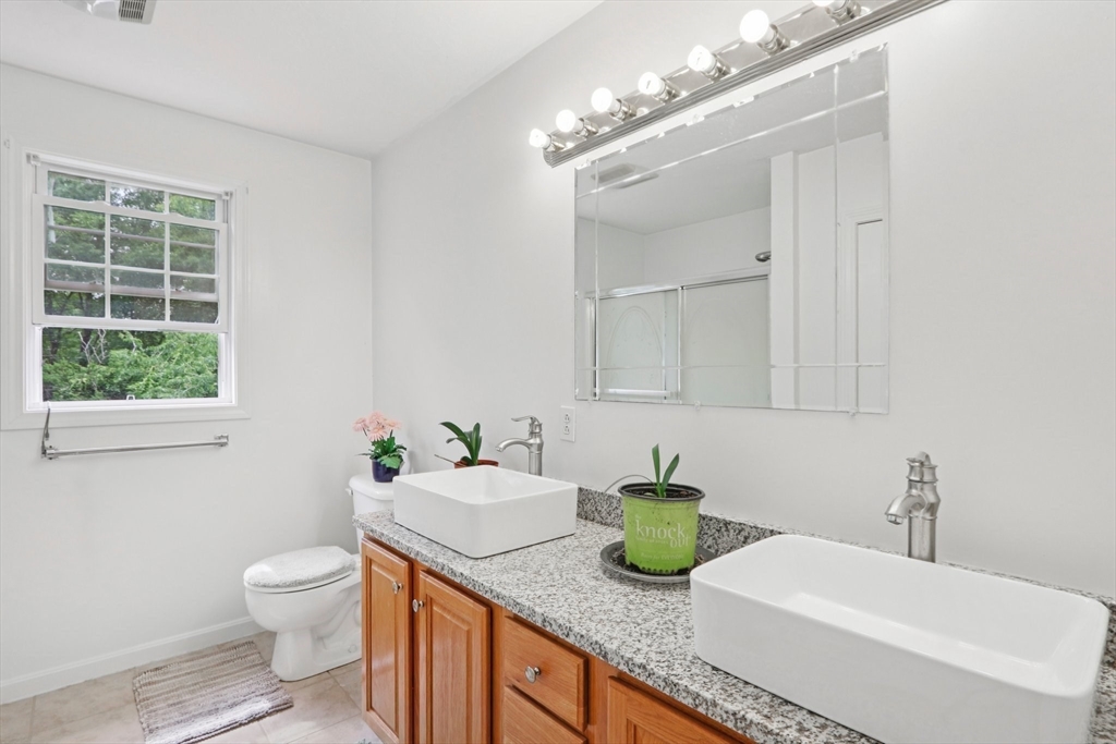 469 North Street Randolph, MA 02368 - Photo 27 of 42 a bathroom with a granite countertop sink a toilet and a mirror