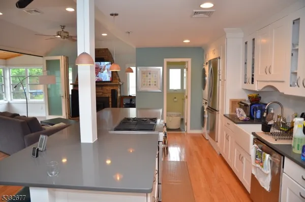 a kitchen with stainless steel appliances granite countertop a refrigerator a sink dishwasher a oven and a dining table with wooden floor