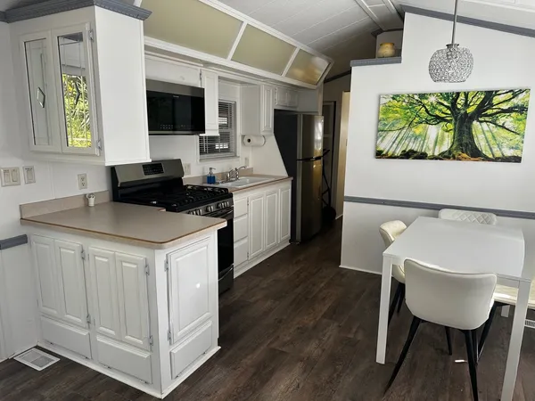 a kitchen with stainless steel appliances granite countertop a stove a sink a microwave a dining table and chairs with wooden floor