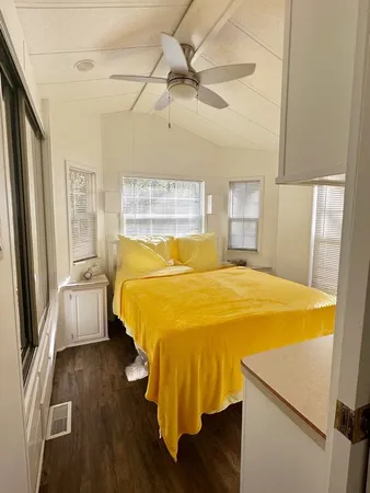 a bed sitting in a bedroom next to a window with kitchen view