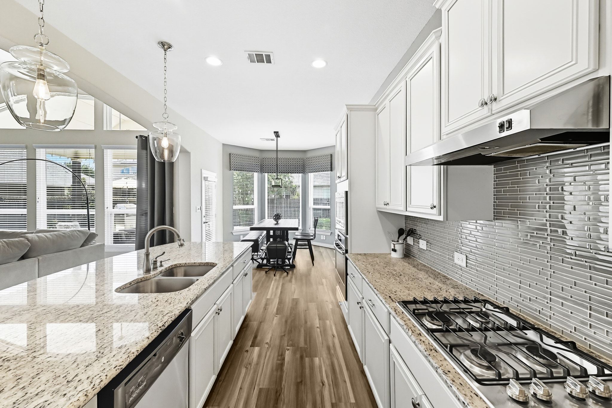 19620 Stanton Drew Pflugerville, TX 78660 - Photo 11 of 33 Kitchen with stainless steel appliances, hanging light fixtures, white cabinetry, dark wood-style flooring, and light stone countertops