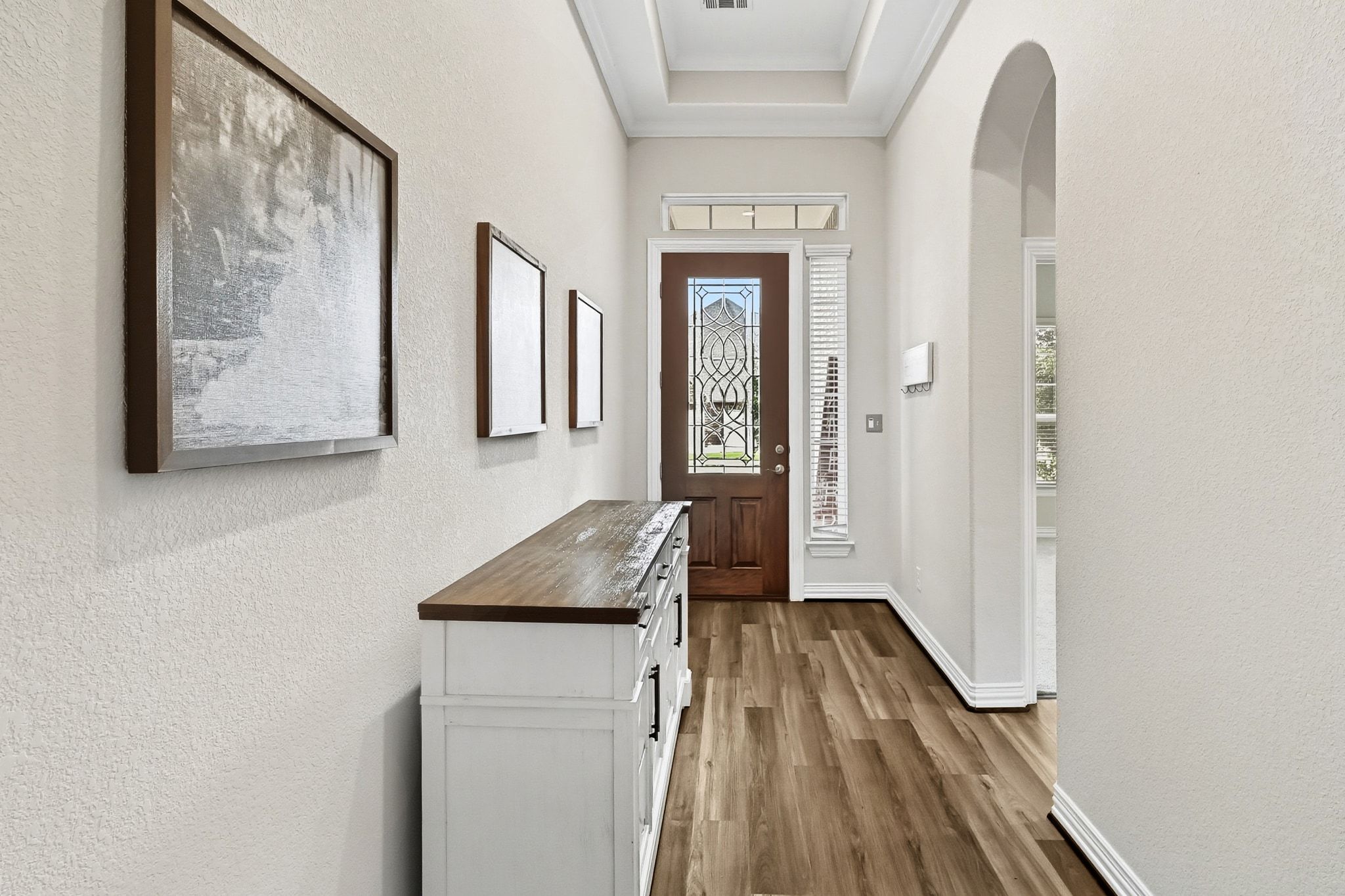 19620 Stanton Drew Pflugerville, TX 78660 - Photo 19 of 33 Entryway with a textured wall, wood finished floors, arched walkways, and a raised ceiling