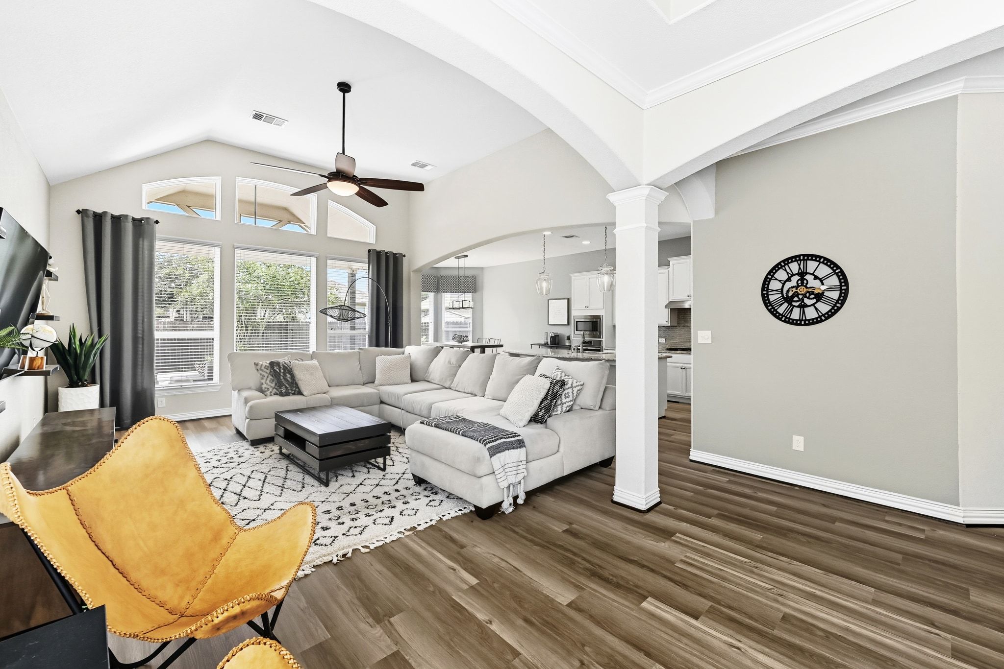 19620 Stanton Drew Pflugerville, TX 78660 - Photo 6 of 33 Living room featuring a ceiling fan, dark wood-style flooring, arched walkways, vaulted ceiling, and ornate columns