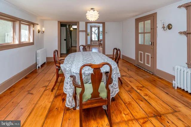 a dining room with wooden floor and large windows