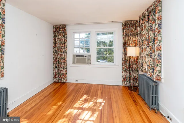 a view of an empty room with a window and wooden floor