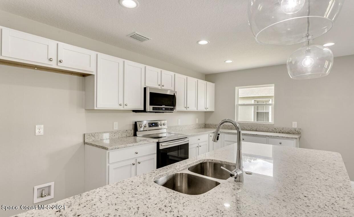 1738 Hydrangea Road Palm Bay, FL 32907 - Photo 12 of 20 a kitchen with stainless steel appliances kitchen island granite countertop a sink a stove and cabinets