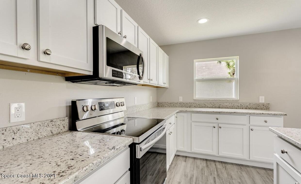 1738 Hydrangea Road Palm Bay, FL 32907 - Photo 14 of 20 a kitchen with granite countertop a sink a stove and microwave with wooden floor