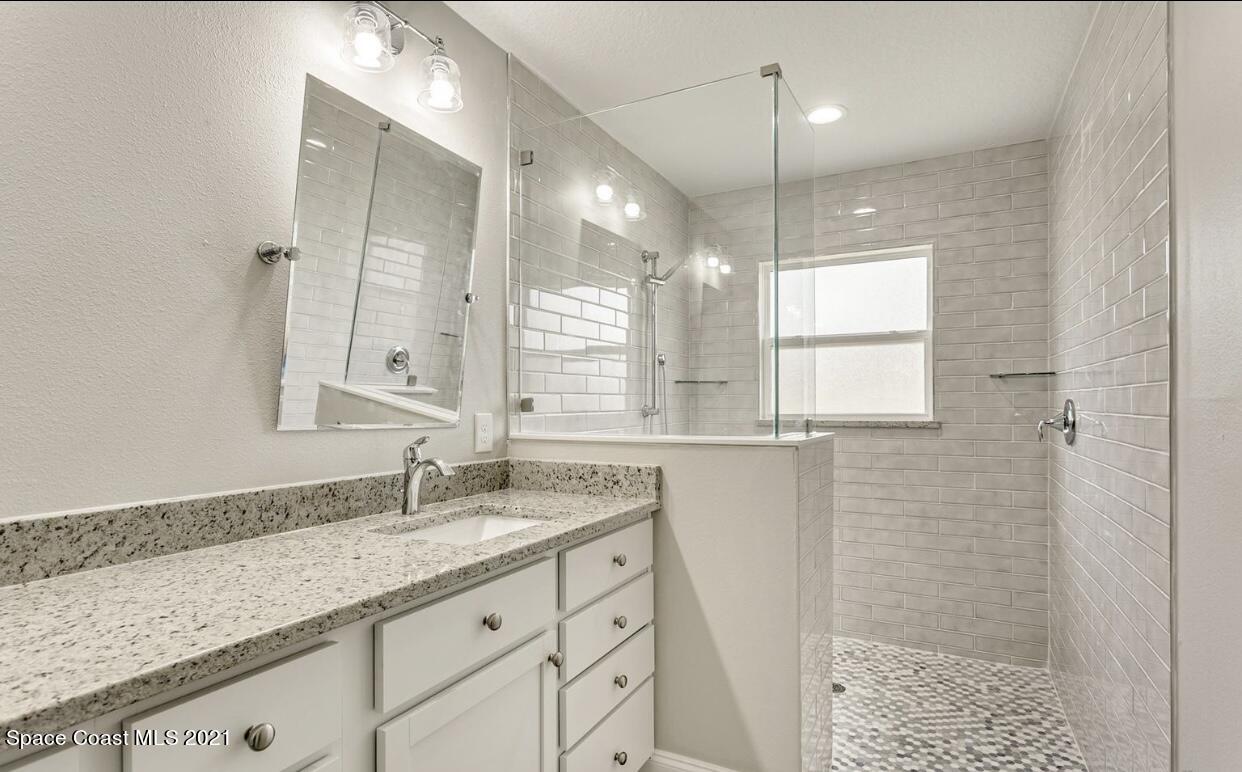 1738 Hydrangea Road Palm Bay, FL 32907 - Photo 19 of 20 a bathroom with a granite countertop sink a shower and a mirror