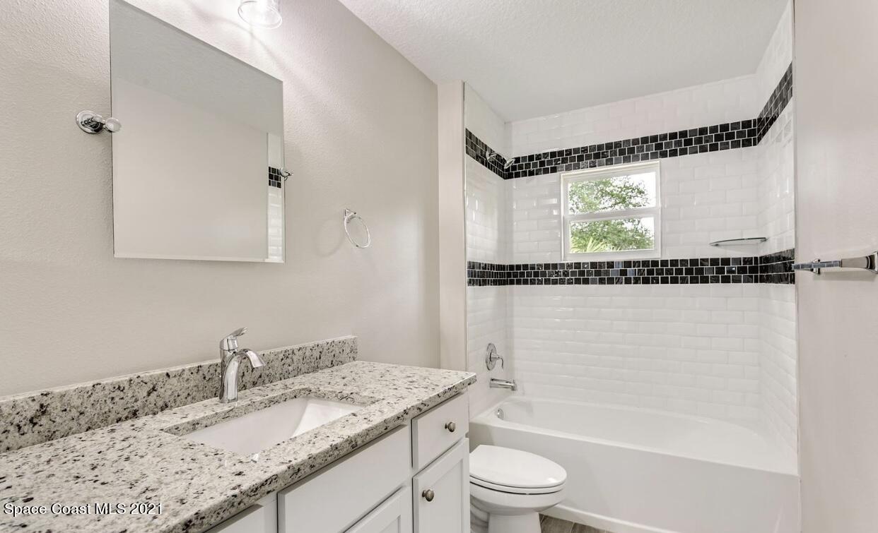 1738 Hydrangea Road Palm Bay, FL 32907 - Photo 6 of 20 a bathroom with a granite countertop sink a mirror and a bathtub