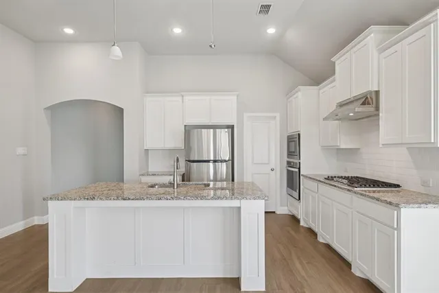 a kitchen with kitchen island a counter top space a sink stainless steel appliances and cabinets