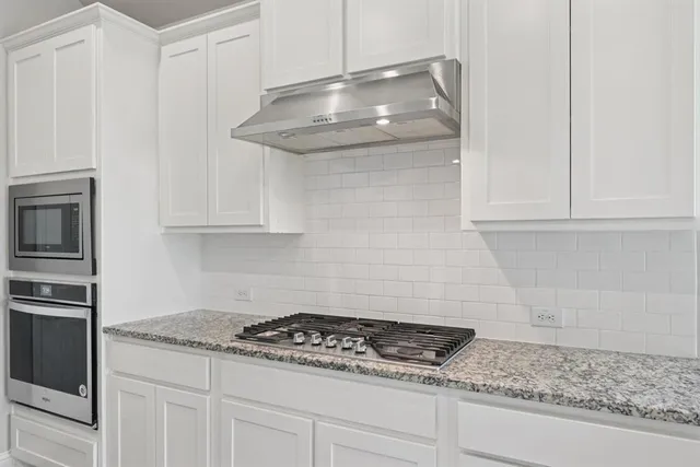 a kitchen with granite countertop white cabinets and stainless steel appliances
