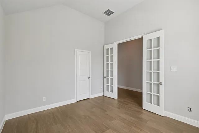 an empty room with wooden floor and entryway