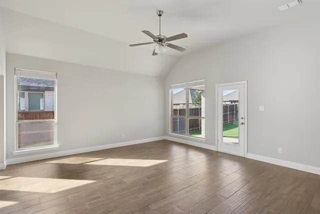a view of an empty room with a window and wooden floor