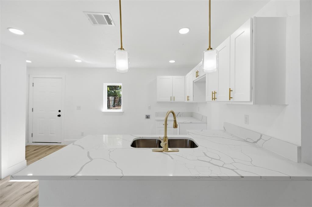 1909 Burchill Road Fort Worth, TX 76105 - Photo 4 of 18 Kitchen island with an undermount double basin sink, gold-finish faucet, and quartz countertop