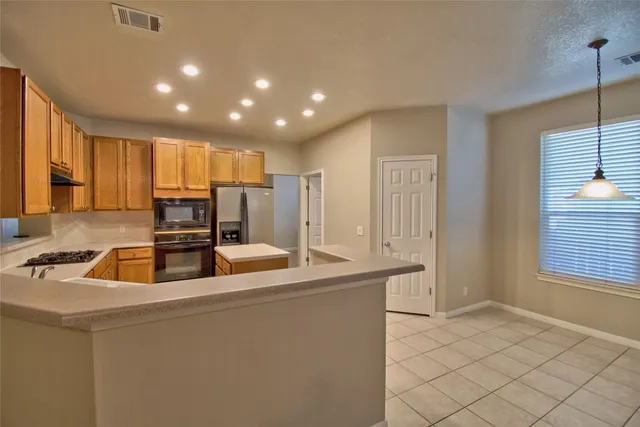 a kitchen with kitchen island granite countertop a sink and a refrigerator