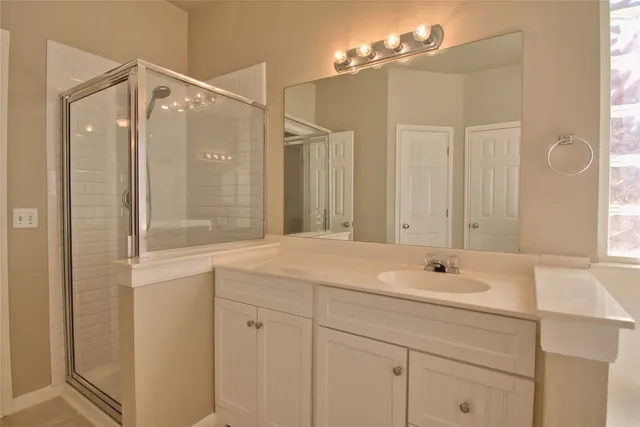 a bathroom with a sink vanity granite tub shower and a mirror