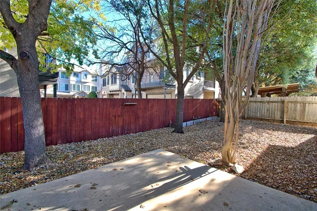 a view of a backyard with large trees and wooden fence
