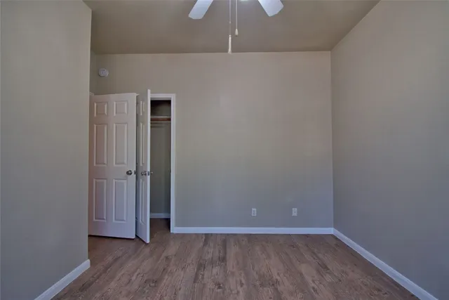 a view of an empty room with closet and wooden floor