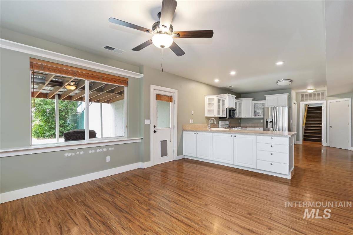 10462 West Lanktree Gulch Road Star, ID 83669 - Photo 31 of 48 Open-concept living space with wood-finish flooring, a contemporary ceiling fan, recessed lighting, and a kitchen featuring white cabinetry, stainless steel appliances, and light-toned countertops