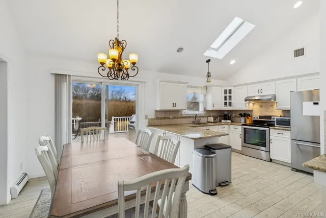 a open kitchen with stainless steel appliances granite countertop a stove a refrigerator a kitchen island a dining table and chairs