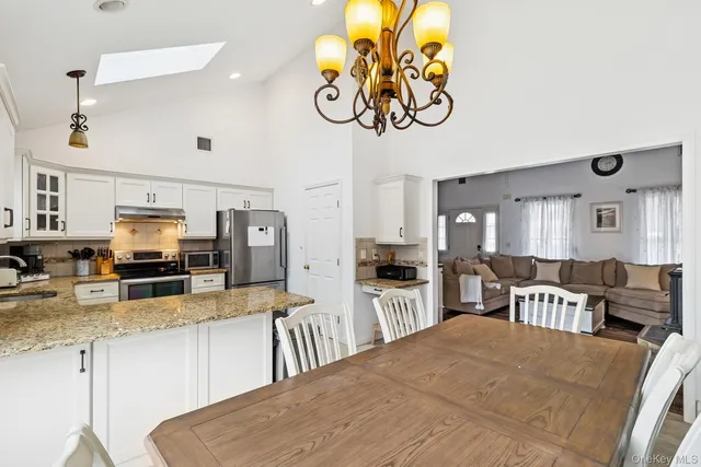 a kitchen with stainless steel appliances granite countertop a stove top oven a sink a dining table and chairs with wooden floor