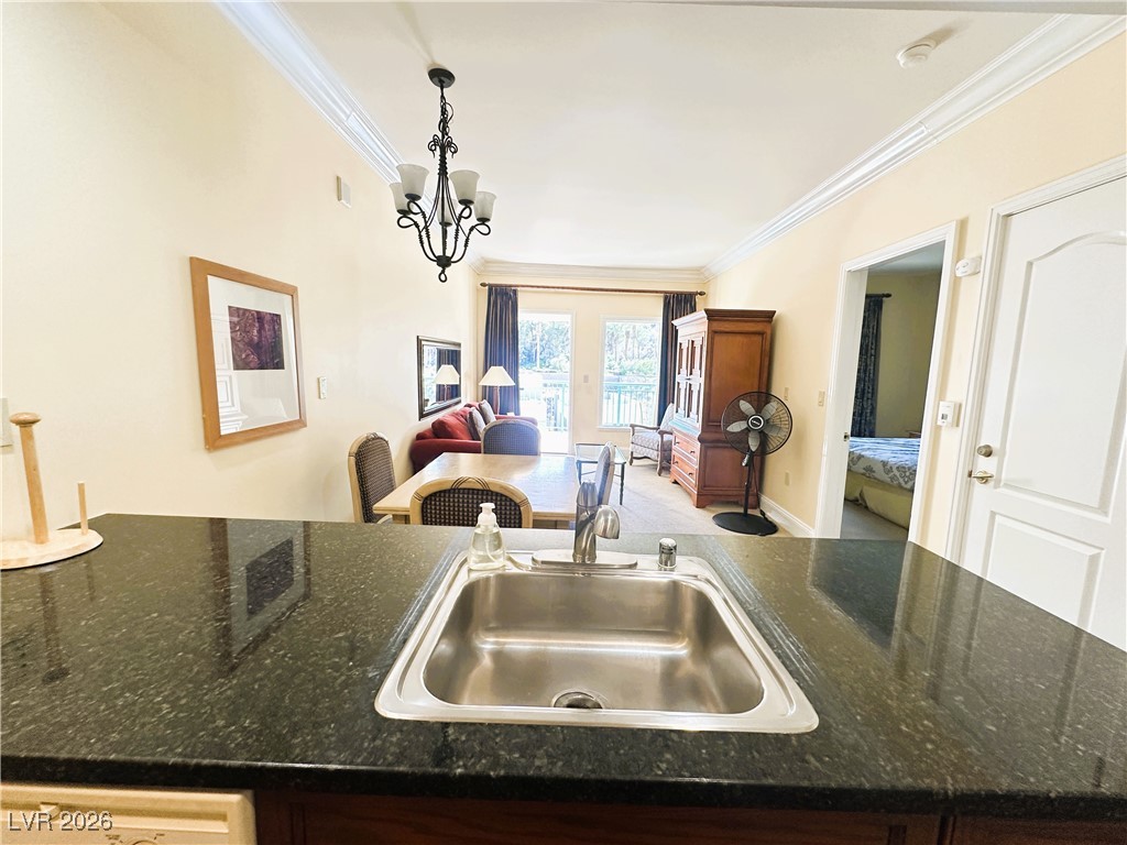 30 Strada Di Villaggio, Unit 531 Henderson, NV 89011 - Photo 42 of 42 Kitchen with crown molding, a chandelier, open floor plan, pendant lighting, and dark stone countertops