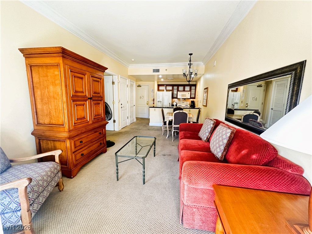 30 Strada Di Villaggio, Unit 531 Henderson, NV 89011 - Photo 15 of 42 Living area with ornamental molding, light colored carpet, and a chandelier