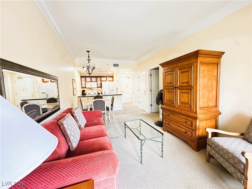30 Strada Di Villaggio, Unit 531 Henderson, NV 89011 - Photo 7 of 42 Living area with crown molding, light colored carpet, and a chandelier