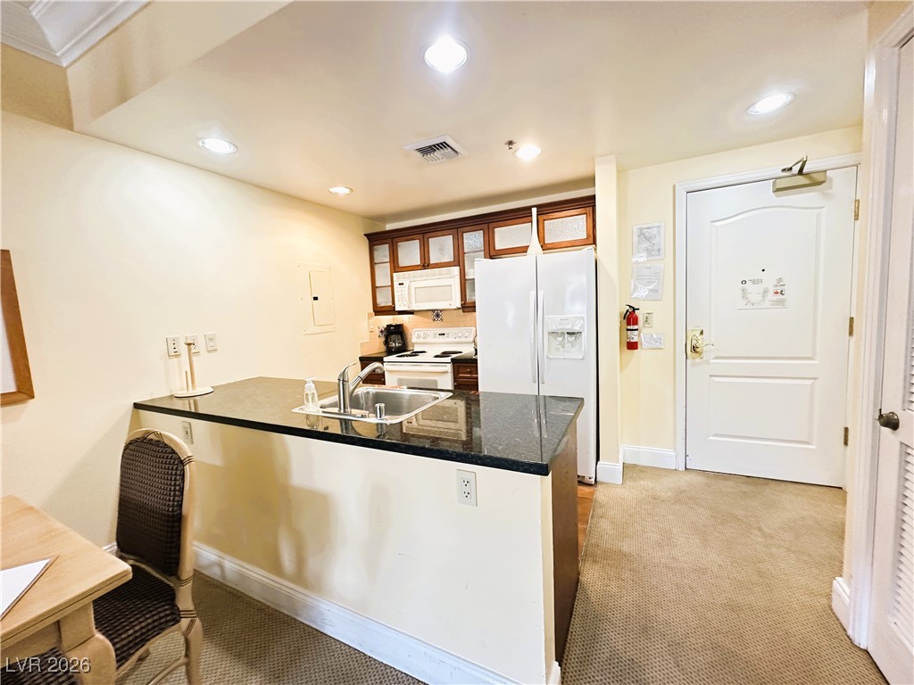 30 Strada Di Villaggio, Unit 531 Henderson, NV 89011 - Photo 10 of 42 Kitchen with a peninsula, white appliances, light colored carpet, recessed lighting, and glass insert cabinets