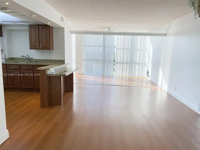 a view of a kitchen with stainless steel appliances granite countertop a stove top oven a sink and a wooden floor