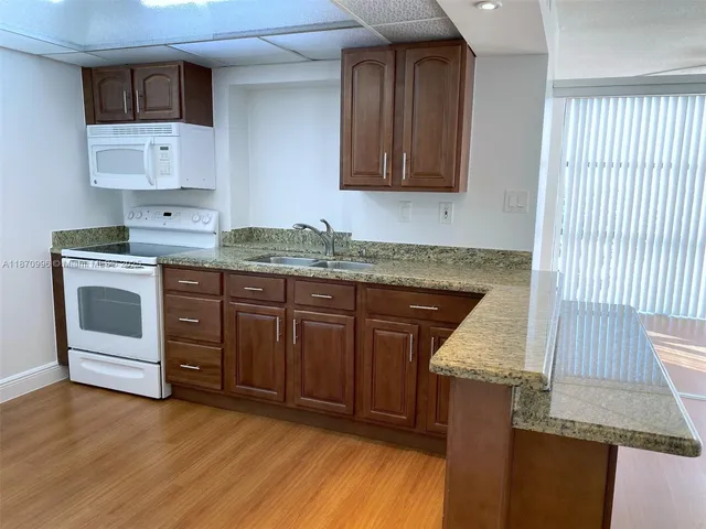 a kitchen with granite countertop a sink cabinets and stainless steel appliances