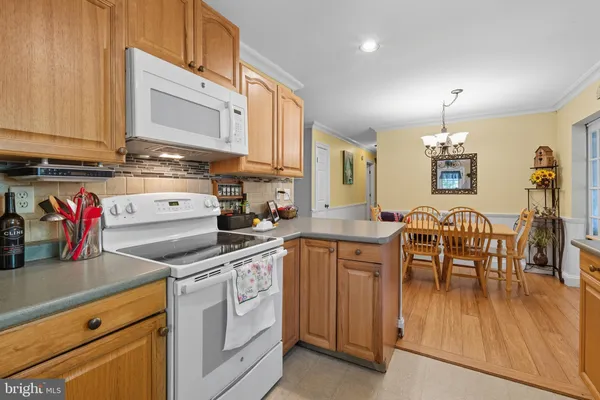 a kitchen with stainless steel appliances granite countertop a stove top oven a sink dishwasher and white cabinets with wooden floor