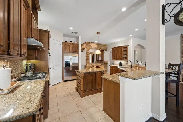 a view of a kitchen with kitchen island stainless steel appliances a sink stove and cabinets