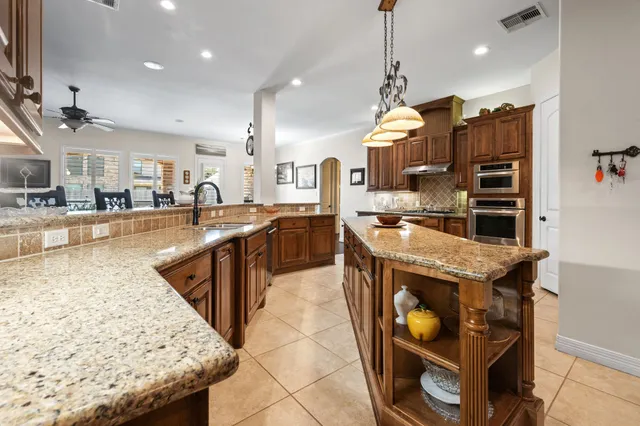 a view of yellow house with a big yard and potted plants
