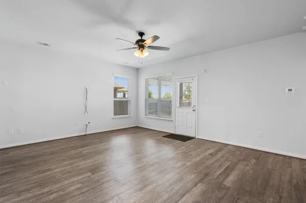 a view of an empty room with a window and wooden floor