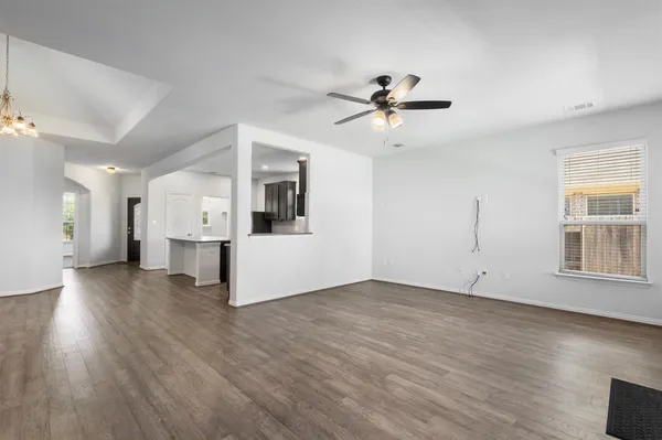 a view of empty room with wooden floor and ceiling fan