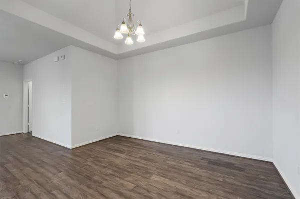a view of a hallway with wooden floor and a chandelier