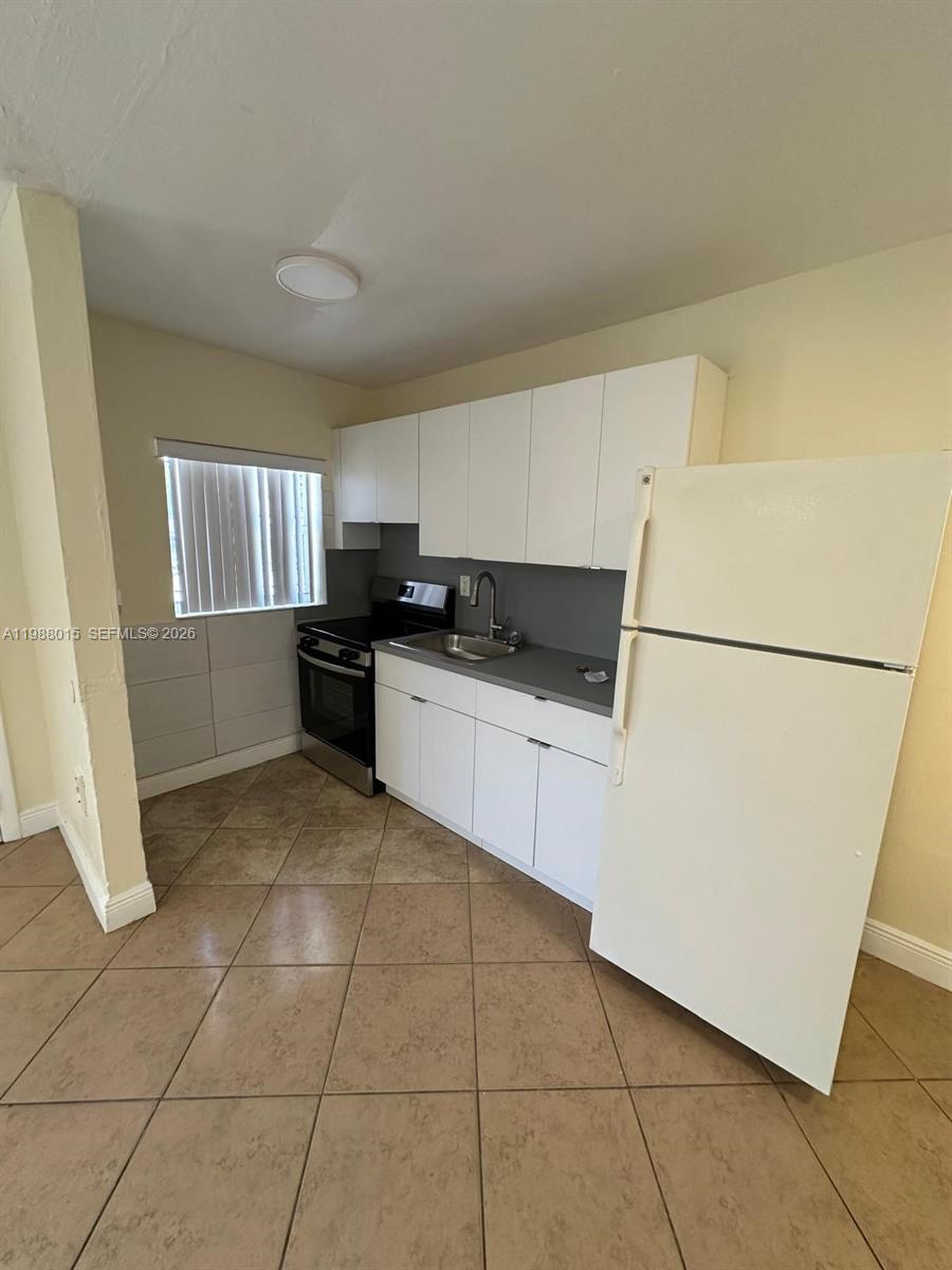100 Northeast 78th Street, Unit 4 Miami, FL 33138 - Photo 6 of 12 a kitchen with granite countertop a refrigerator and a sink