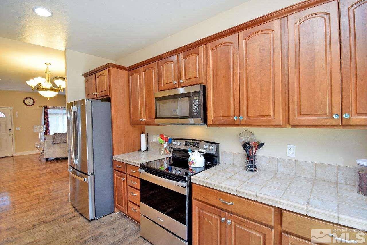 2735 Gulling Court Reno, NV 89503 - Photo 5 of 30 a kitchen with stainless steel appliances granite countertop a refrigerator a sink dishwasher and wooden cabinets with wooden floor