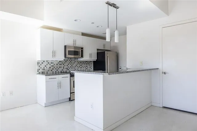 a kitchen with stainless steel appliances granite countertop a sink and a refrigerator