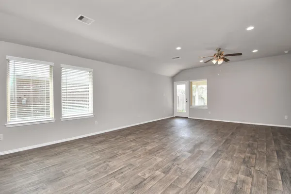 a view of an empty room with a window and wooden floor